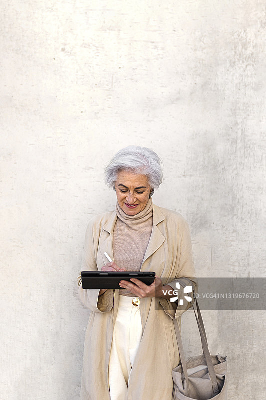 在购物区使用平板电脑的女人在墙前图片素材