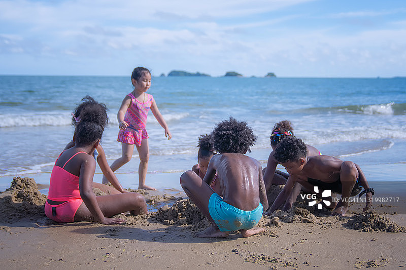 一群非洲裔美国孩子在海滩上玩沙子。图片素材