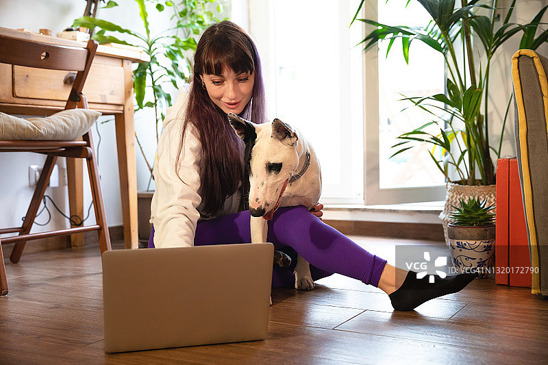一个女人和她的狗在家里使用笔记本电脑图片素材