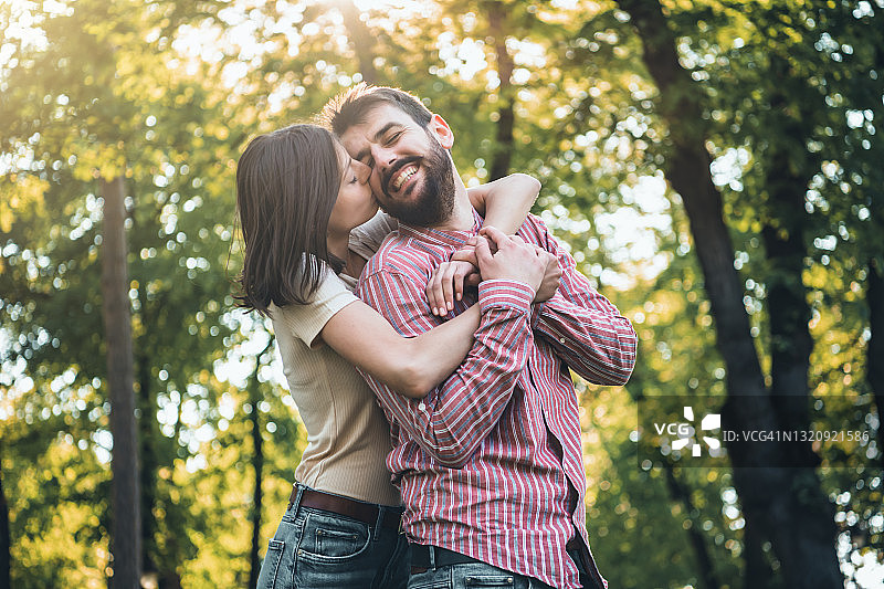 快乐的年轻情侣在公园接吻。图片素材