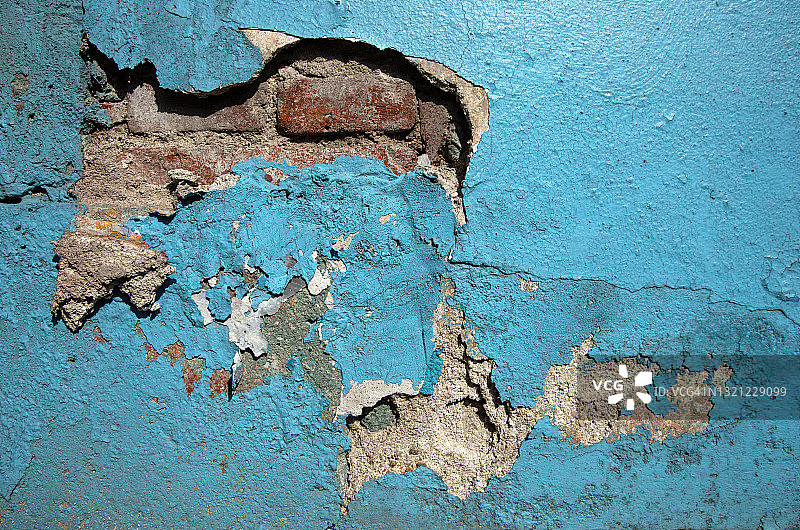 灰泥和砖墙开裂剥落，漆成亮蓝色图片素材