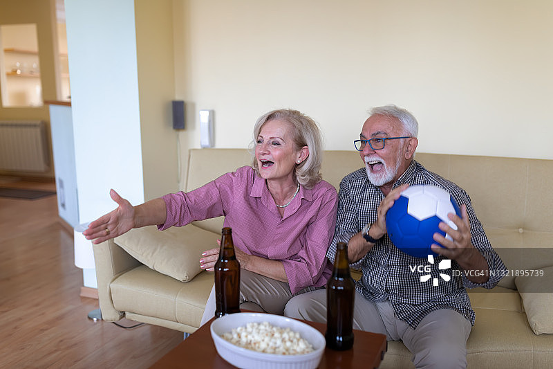 一位老人和他的妻子正在看一场足球赛。图片素材