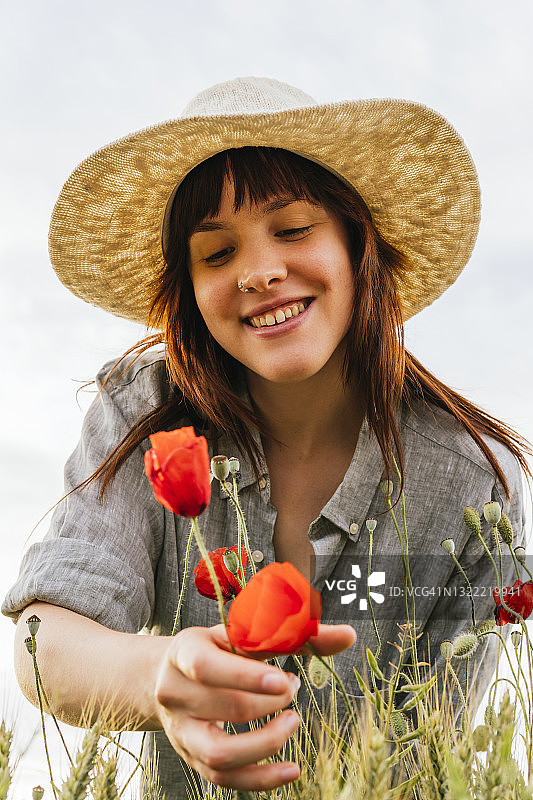 微笑的女人戴着帽子摘罂粟花图片素材