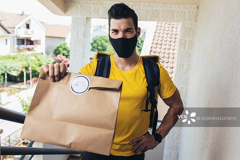 戴着防护面具的男子在网上送杂货订单。图片素材
