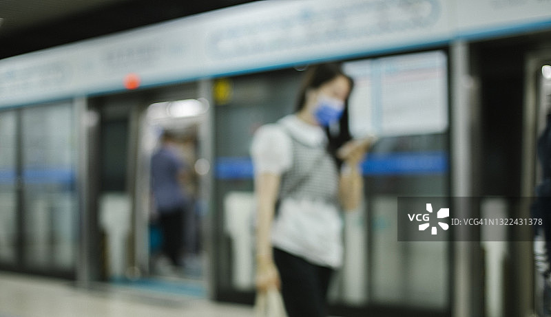 一群带着防护口罩的忙碌通勤者在北京地铁里行走图片素材