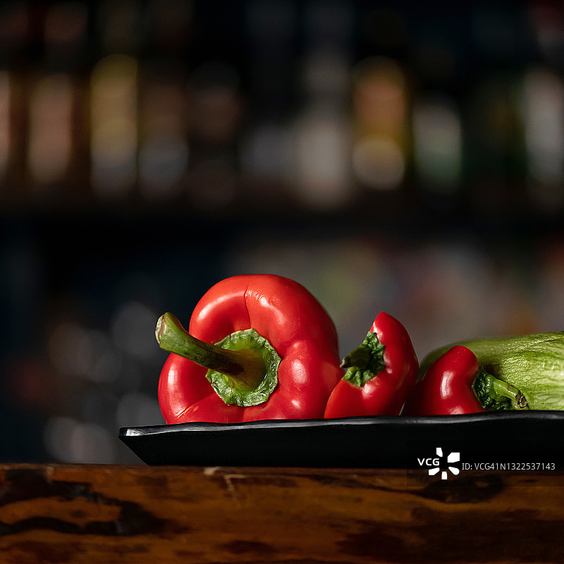 新鲜蔬菜。红色灯笼椒，辣椒或红辣椒和西葫芦在黑色模糊的背景。有机食品的概念。侧视图。复制空间在顶部的图像。维生素类产品，热量含量最低图片素材