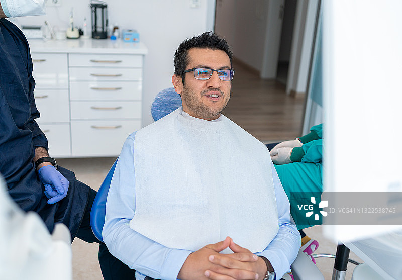 牙医正在检查年轻男子的牙齿。牙科医生检查牙科x光片。男牙医向病人讲解牙齿x光片图片素材
