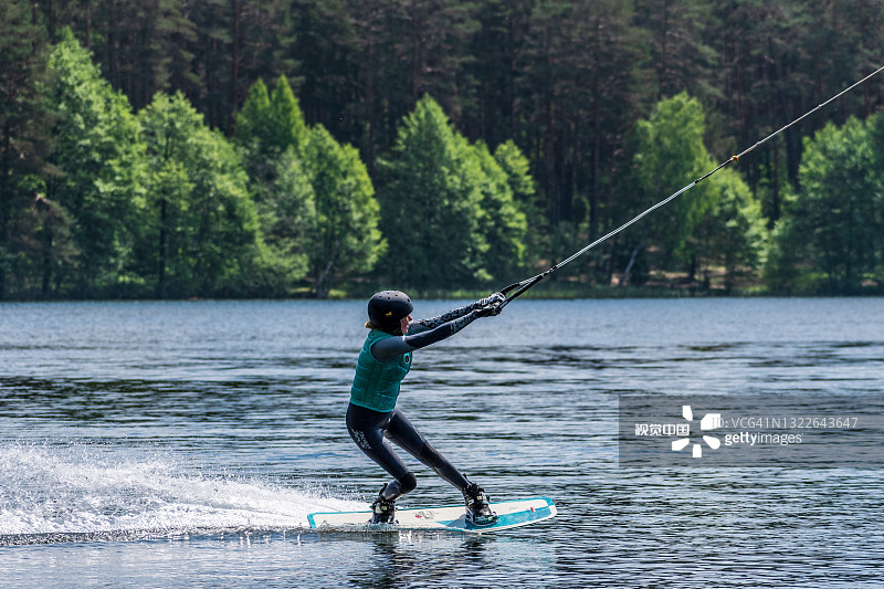 戴着头盔和救生衣的女孩在湖上玩滑水板图片素材