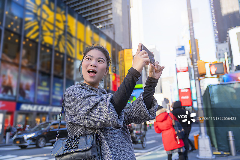 聪明的亚洲成熟的成年女性女性旅行者休闲装放松休闲手持式地图相机智能手机行走观光纽约曼哈顿时代广场图片素材