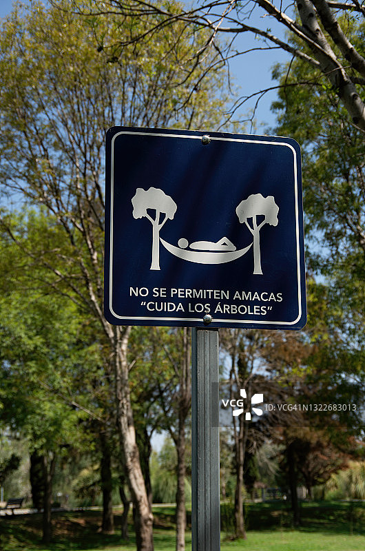 西班牙语标牌上写着“禁止使用吊床”(“爱护树木”)图片素材