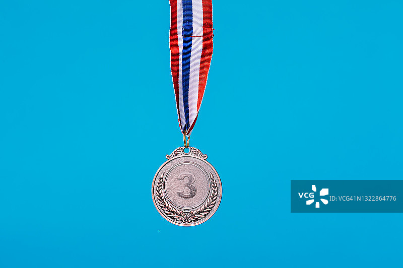 体育比赛第三名铜牌悬挂，蓝色背景图片素材