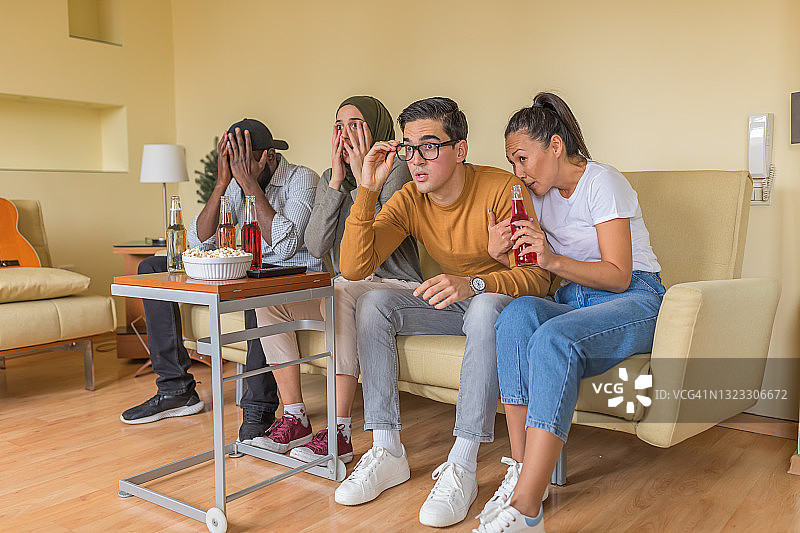 一群年轻的多元文化朋友在现代公寓里看电影。图片素材