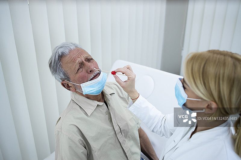 在COVID-19流行期间，一位老人在医生的办公室接受PCR鼻部测试。图片素材