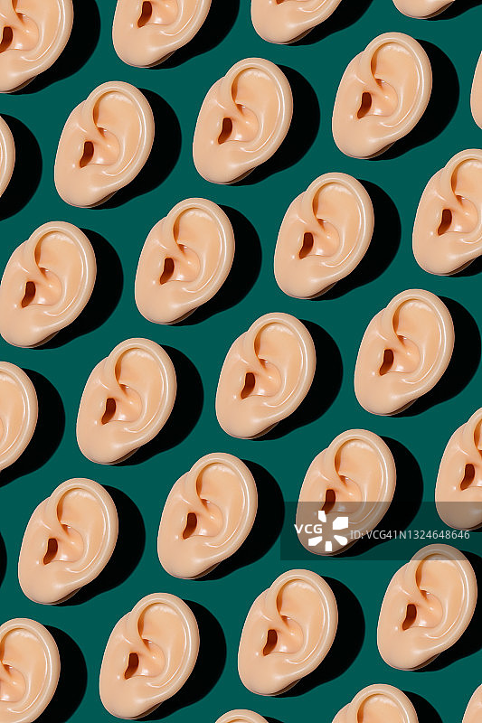 绿色上整齐排列的人类耳朵模型图片素材