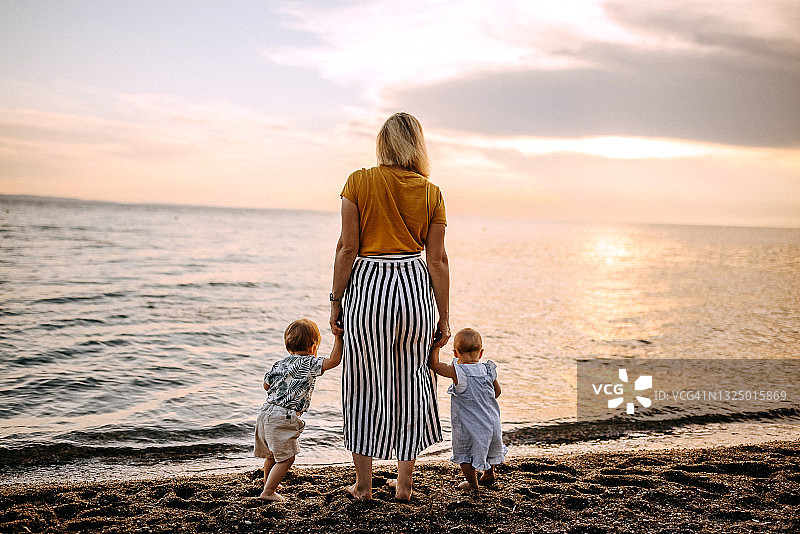 母亲带着两个孩子在海滩上欣赏日落图片素材