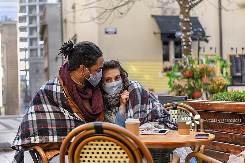 英俊的非洲男子和他美丽的女友坐在餐厅里，享受着一杯热咖啡。图片素材