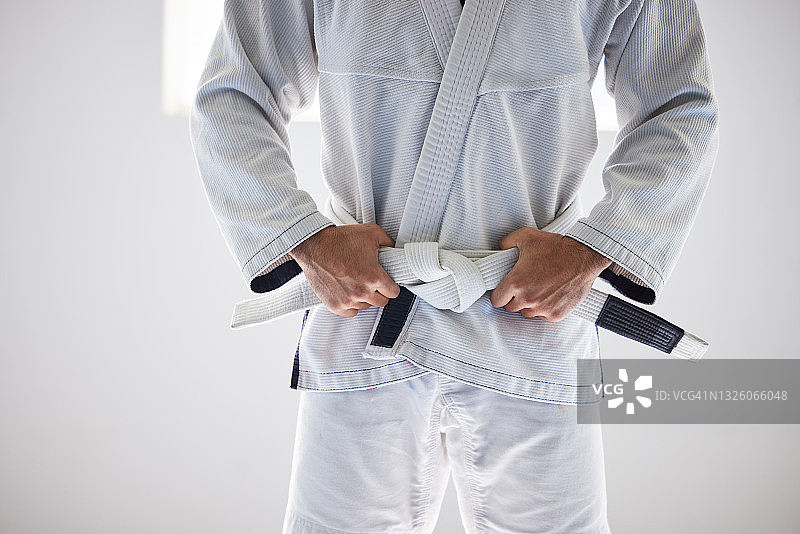 一个不知名的男性武术家站在他的手在他的皮带在健身房的裁剪镜头图片素材