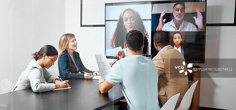 这是一组不同的商务人士通过视频聊天坐在会议室里与他们的国际同事开会的照片图片素材