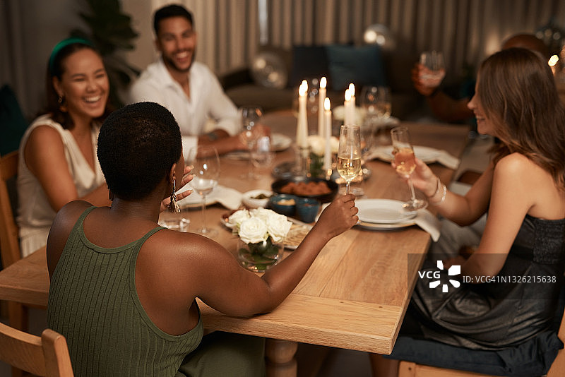 照片中，一群不同的朋友坐在一起，在一个晚宴上享用一杯香槟图片素材