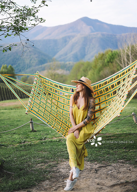 独自一人的女游客穿着夏装，戴着一顶帽子，正在山间的绿茶种植园中休息，寻找冒险，享受大自然图片素材