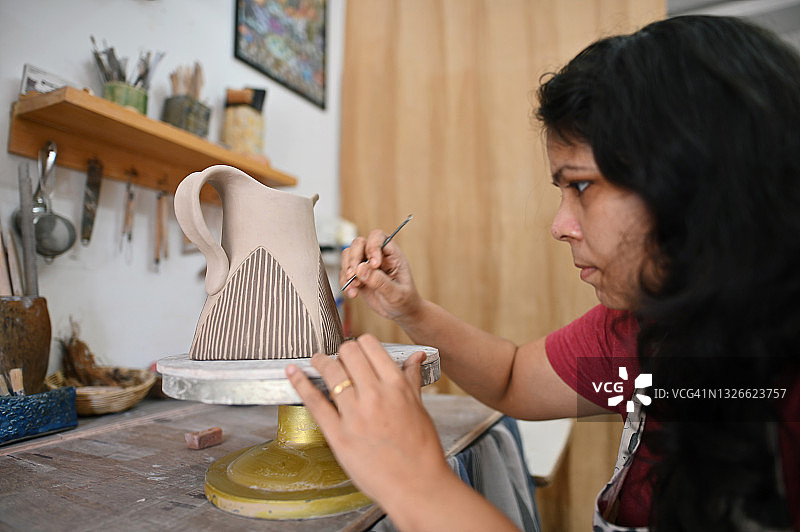 女艺术家在陶瓷花瓶上雕刻图案图片素材