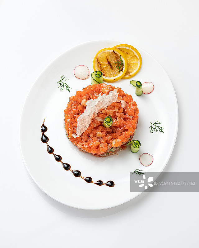搭配红鲟鱼和蔬菜的节日沙拉或小吃。白色盘子上的三文鱼片，柠檬片和黄瓜卷。前视图。垂直格式图片素材