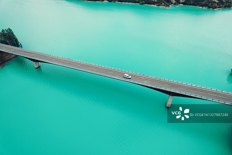 在比利牛斯山脉的蓝色湖泊上驾驶的汽车的无人机视图。图片素材