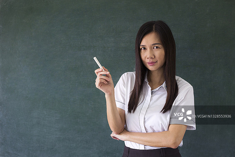 女教授手持粉笔站在黑板前图片素材