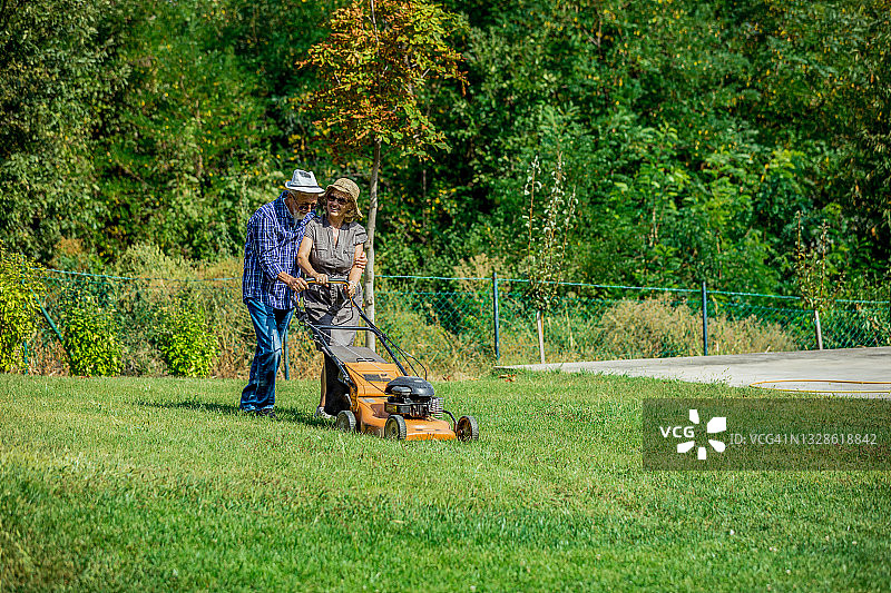 男人和女人用割草机在一个乡村花园工作图片素材