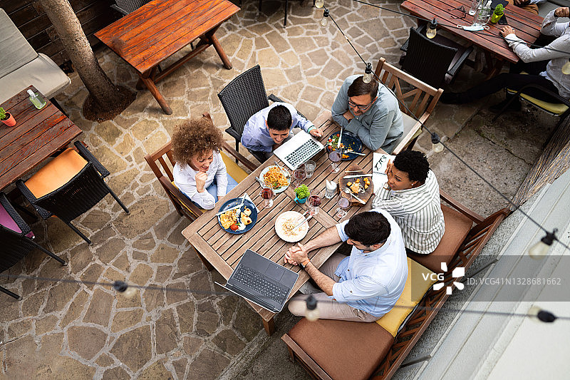 俯视图，一个多民族的商务人士有一个会议在一个户外餐厅的午餐图片素材