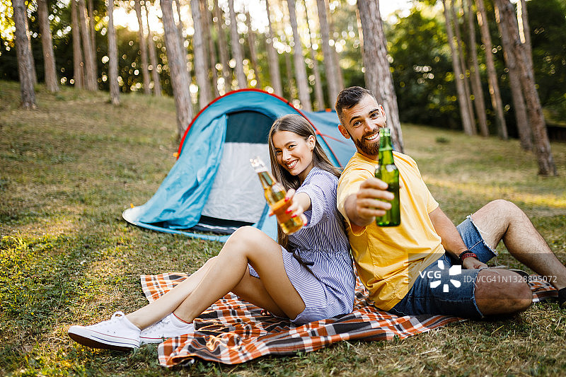 年轻夫妇露营，喝啤酒，玩得很开心图片素材