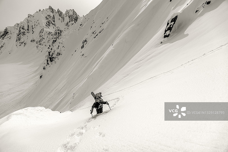偏远地区的滑雪者爬上陡峭的雪坡图片素材