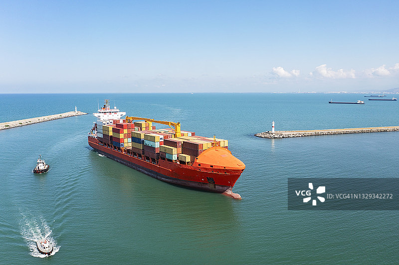 集装箱货轮与拖船接近港口鸟瞰图。图片素材