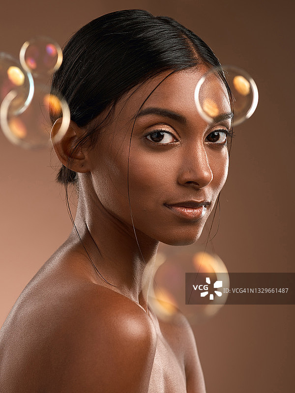 一个年轻迷人的女人的肖像与泡沫的棕色背景图片素材