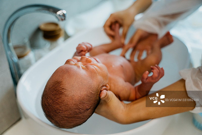 婴儿护理员在浴室为新生儿洗澡图片素材