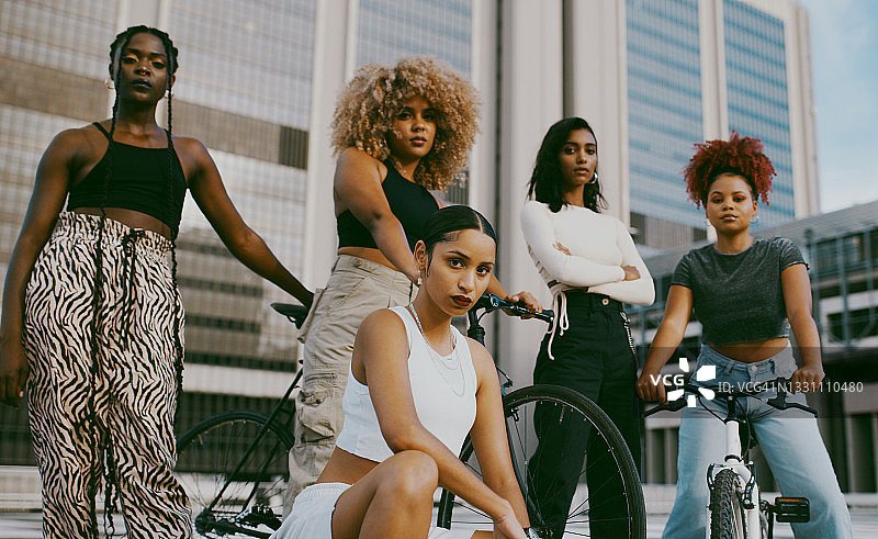 白天，一群不同的女性在城市里骑着自行车摆姿势图片素材