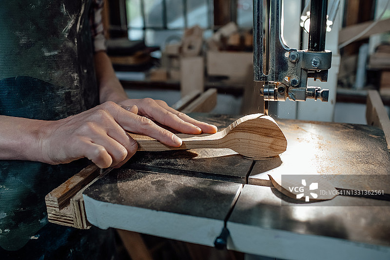 一个年轻的欧洲人在他的木工车间做一个木制勺子。手的特写图片素材