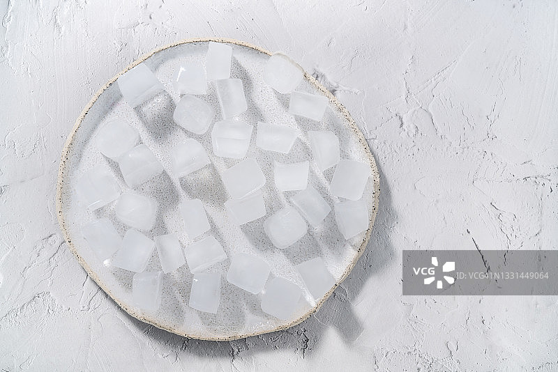 冰块放在白色的圆盘子里，背景是白色的图片素材