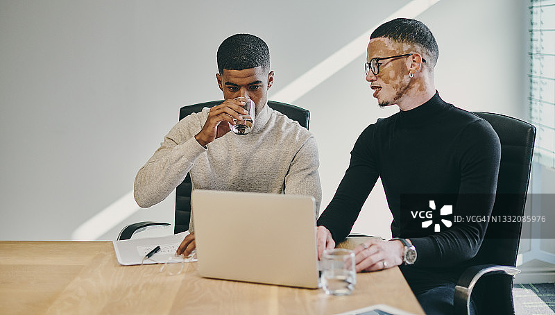 两名年轻的商人在现代办公室开会时使用笔记本电脑图片素材