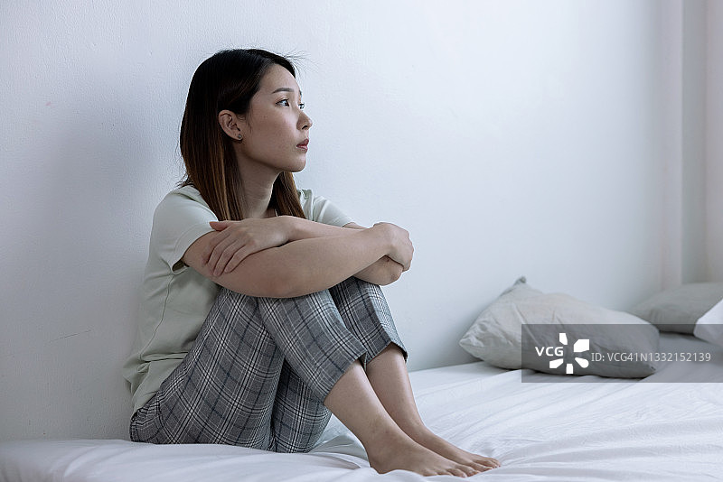 患有抑郁症的亚洲少女独自坐在卧室里。图片素材