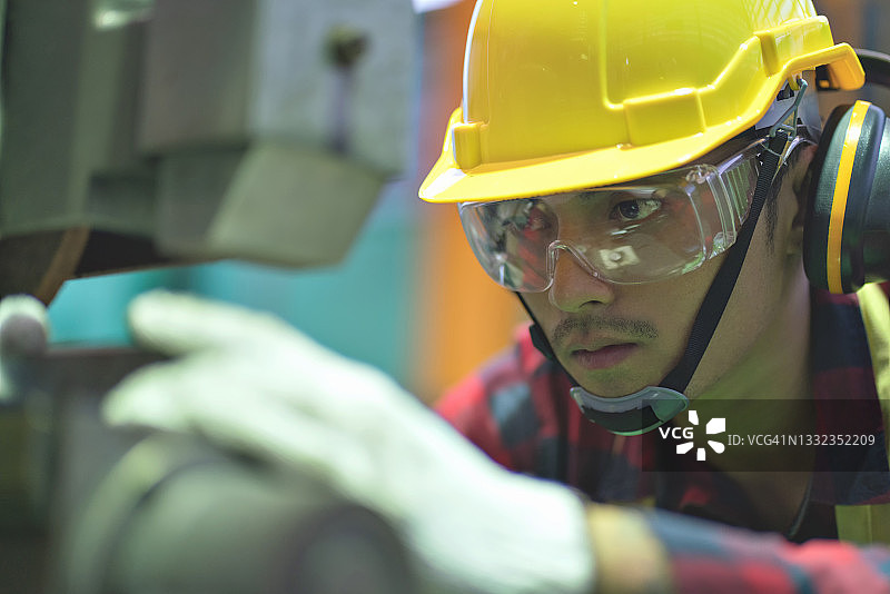 亚洲工人戴着安全帽在工厂机器上工作图片素材