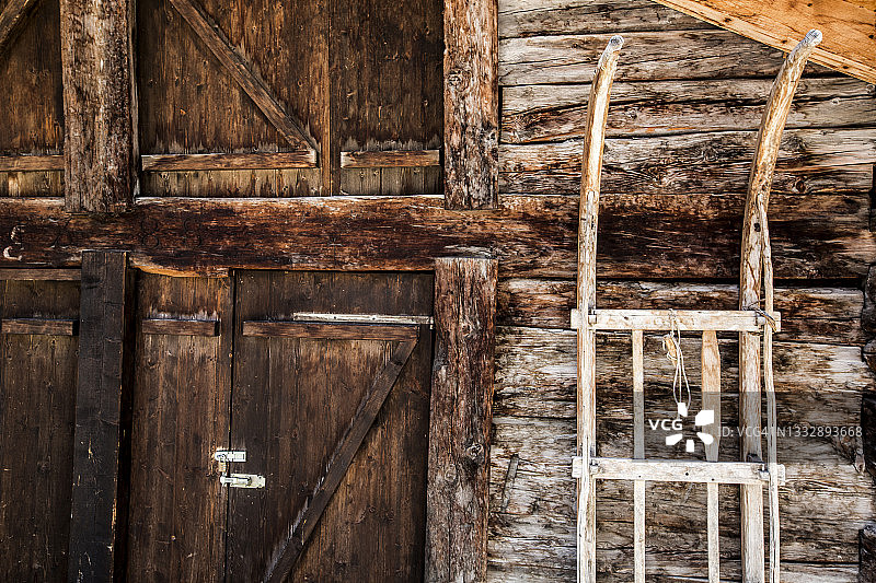 传统的木制雪橇在一扇质朴的木门前图片素材