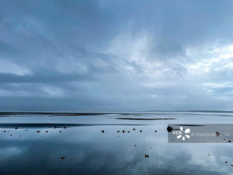 广阔的拍摄滩涂在戏剧性和情绪化的风暴云被反映在水中。图片素材