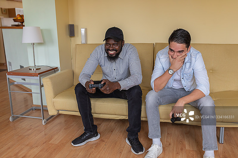 一位非洲种族的大胡子快乐男子正在和他的朋友玩电子游戏。图片素材