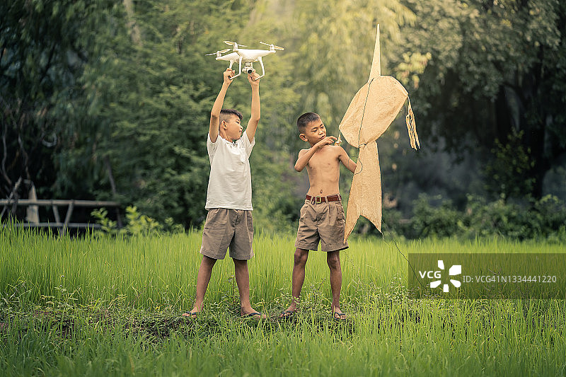 两个男孩在讨论无人机和风筝哪个更有趣。图片素材