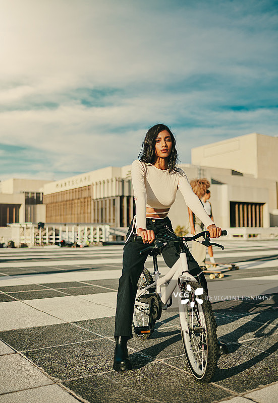一个骑自行车的年轻女人在城市里图片素材