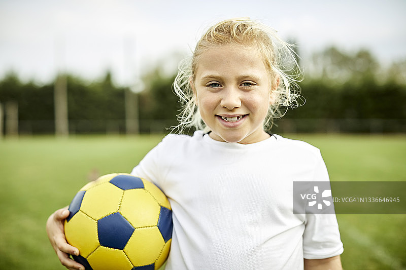 快乐女孩的肖像与足球在场上图片素材