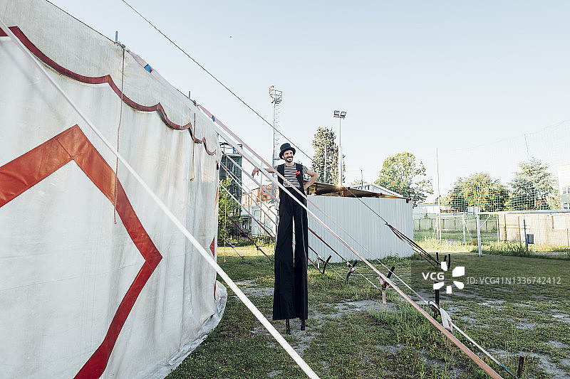 马戏团男演员站在帐篷边，踩着高跷图片素材