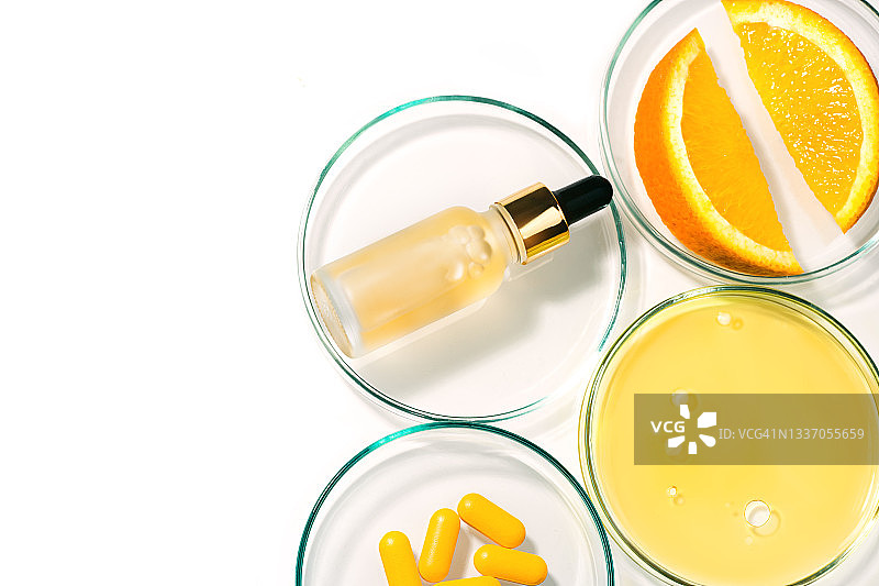 美容概念的维生素C面部精华在化妆品瓶滴和油和果汁与维生素C在白色背景。图片素材