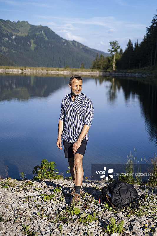 在阳光明媚的日子里，一个微笑的男人站在湖边图片素材